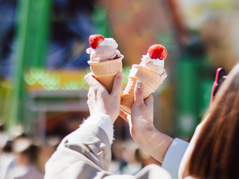 Couple holding up Strawberry Sundae in front of The Common Good's Strawberry Sundae Stalls at Ekka